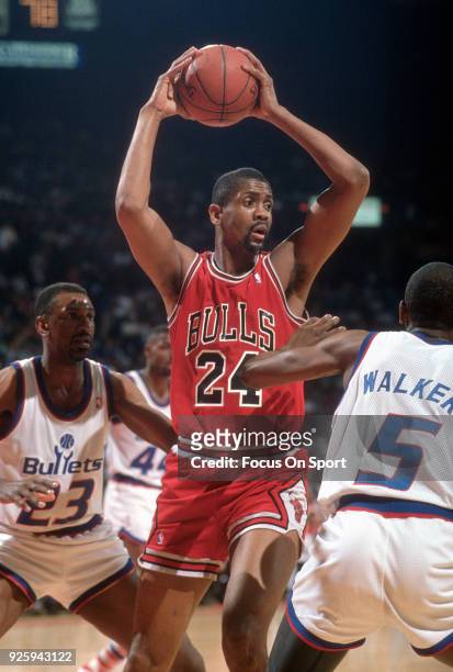 Bill Cartwright of the Chicago Bulls looks to pass the ball over the top of Darrell Walker of the Washington Bullets during an NBA basketball game...