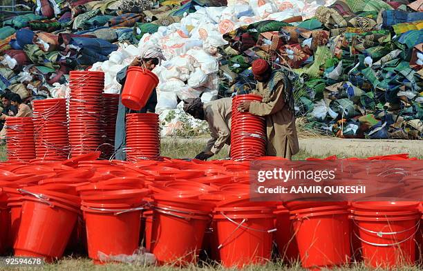 Pakistani workers arrange buckets for internally displaced Pakistani civilians, to be distributed with other relief material to internally displaced...