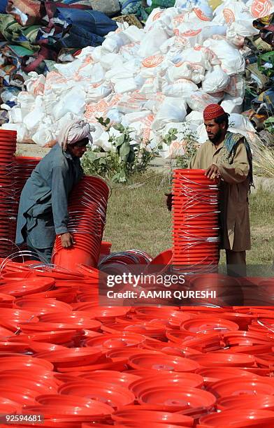 Pakistani workers arrange buckets for internally displaced Pakistani civilians, to be distributed with other relief material to internally displaced...