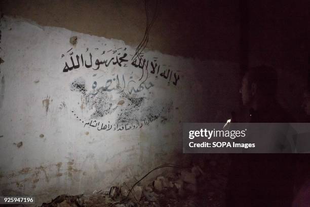 Aleppo's "representative for reconciliation" Fadi Ahmad Ismail points out graffiti he says proves Al Nusra controlled Bustan al Qasr neighbourhood....