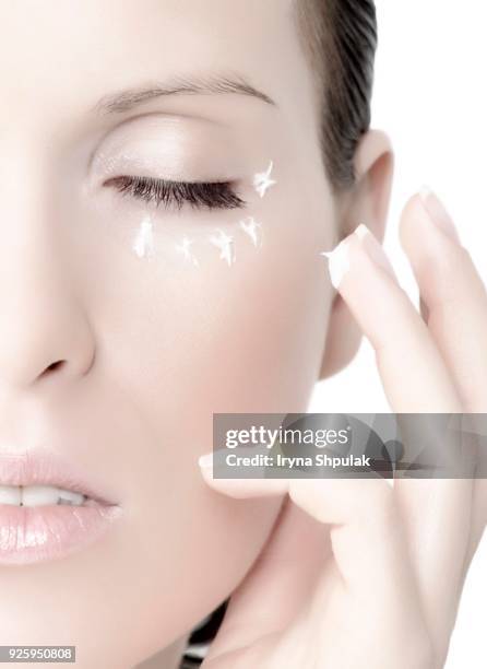 young woman applying cream, with cream under the eyes and on the finger - woman applying cotton ball stock pictures, royalty-free photos & images