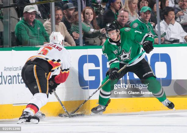 Tyler Pitlick of the Dallas Stars tries to keep the puck away against Mark Giordano of the Calgary Flames at the American Airlines Center on February...