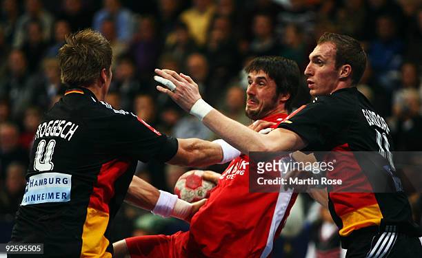 Michael Knudsen of Denmark and Oliver Roggisch and Holger Glandorf of Germany battle for the ball during the Supercup 2009 game between Sweden and...