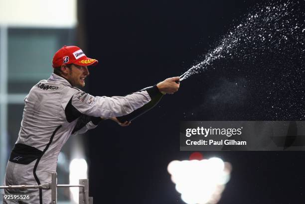 Jenson Button of Great Britain and Brawn GP celebrates on the podium after finishing third during the Abu Dhabi Formula One Grand Prix at the Yas...