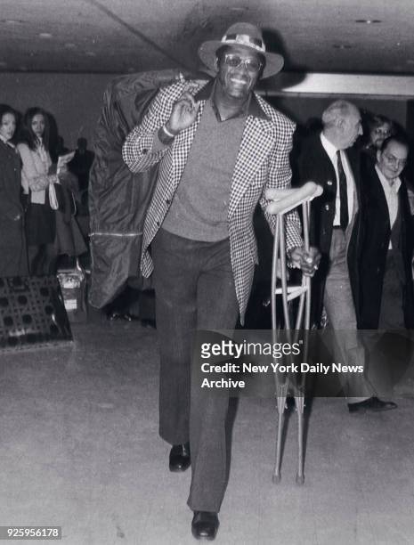 Basketball great Willis Reed caries his crutches.