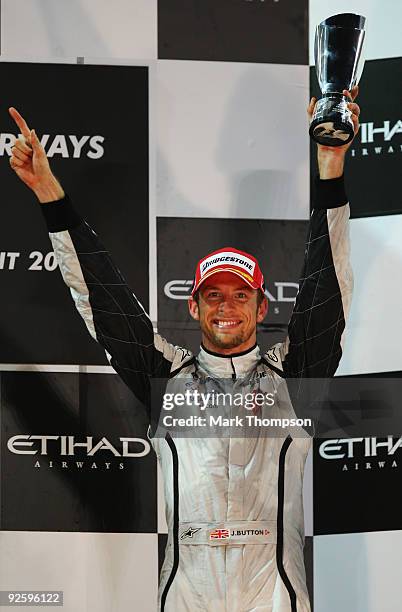 Jenson Button of Great Britain and Brawn GP celebrates on the podium after finishing third during the Abu Dhabi Formula One Grand Prix at the Yas...