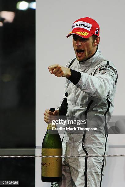 Jenson Button of Great Britain and Brawn GP celebrates on the podium after finishing third during the Abu Dhabi Formula One Grand Prix at the Yas...