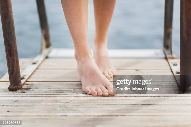 bare feet of woman standing on jetty - womans bare feet fotografías e imágenes de stock