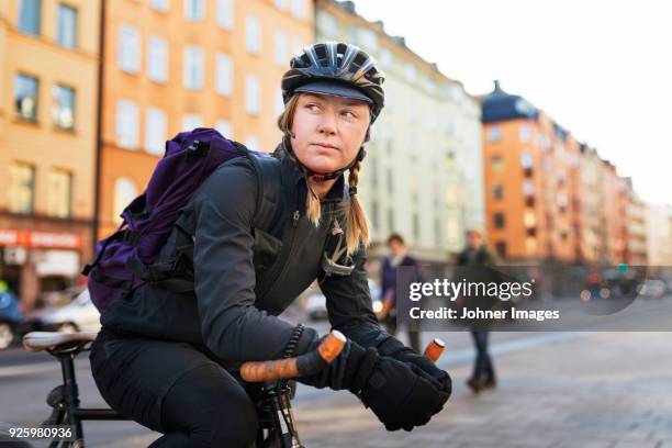 woman leaning on bicycle in street - fahrradkurier stock-fotos und bilder
