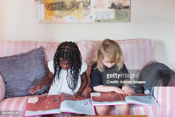 Girls reading childrens books on sofa