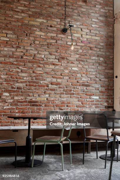 empty tables and chairs against brick wall - bar wall stock-fotos und bilder