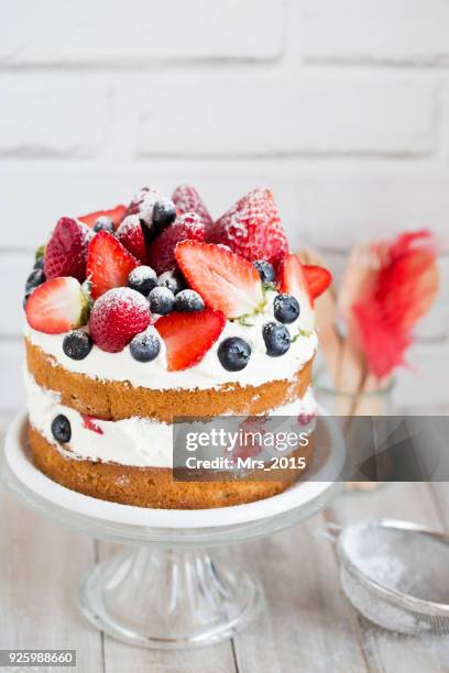 sponge cake with strawberries, blueberries and cream on a cake stand - cakestand stock-fotos und bilder