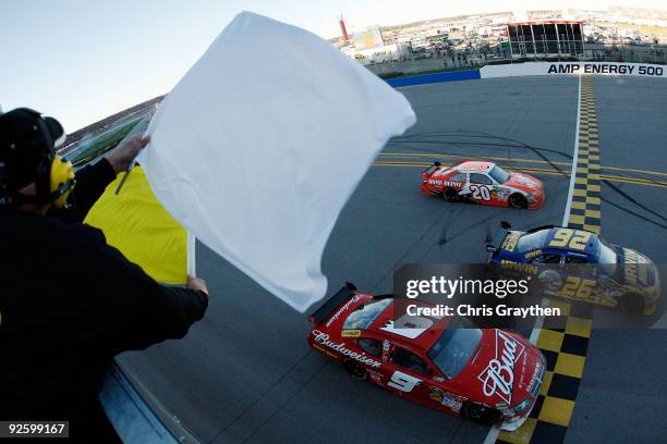 Jamie McMurray, driver of the IRWIN Marathon Ford, takes the yellow and white flag as he crosses the finish line in the final lap of the NASCAR...