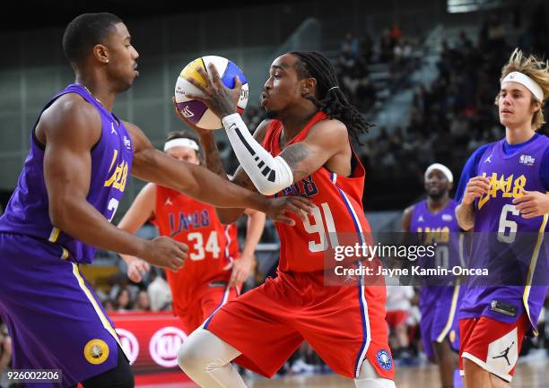 Singer Justin Beiber looks on as American rapper Quavo drives to the basket past actor Michael B Jordan during the 2018 NBA All-Star Game Celebrity...