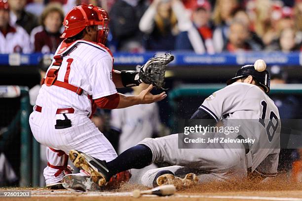 Johnny Damon of the New York Yankees slides safely into home on a sacrifice fly by Jorge Posada ahead of the throw to Carlos Ruiz of the Philadelphia...