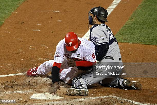 Ryan Howard of the Philadelphia Phillies slides safely into home to score against catcher Jorge Posada of the New York Yankees on a RBI single by...