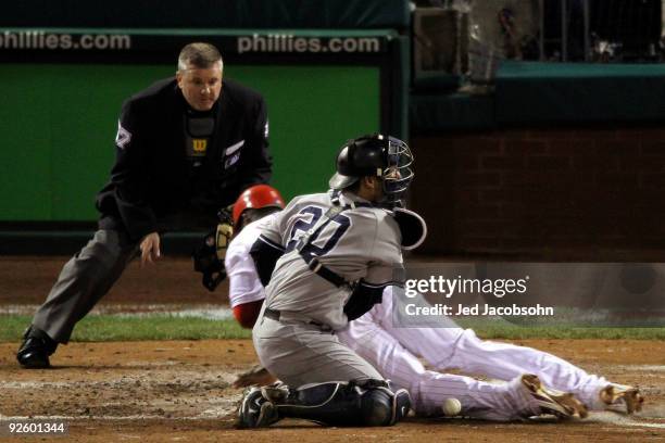 Ryan Howard of the Philadelphia Phillies slides safely into home to score against catcher Jorge Posada of the New York Yankees on a RBI single by...