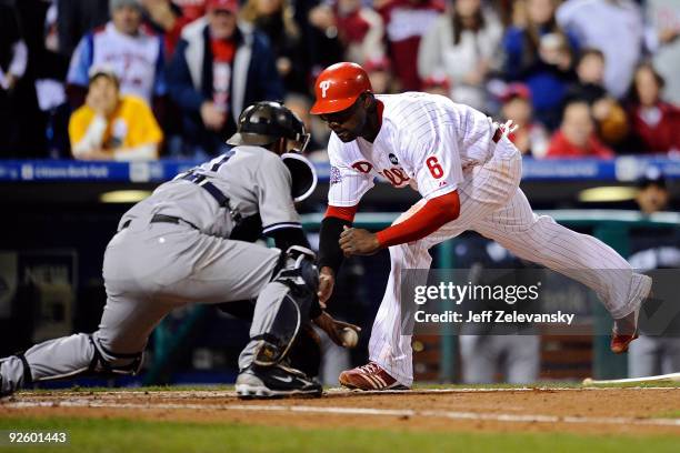 Ryan Howard of the Philadelphia Phillies slides safely into home to score against catcher Jorge Posada of the New York Yankees on a RBI single by...