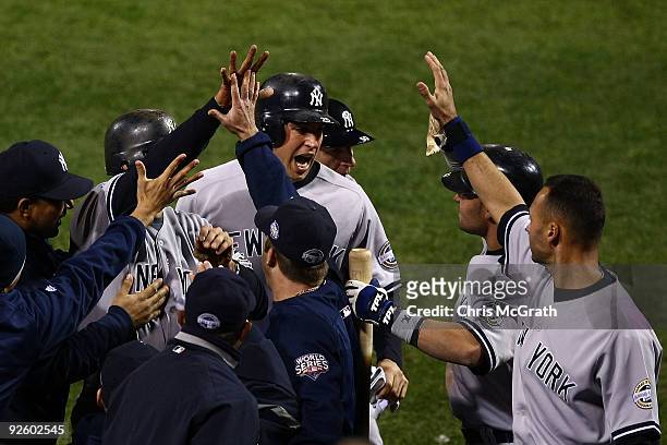 Mark Teixeira of the New York Yankees celebrates with his teammates at the dugout after he scored on a 2-run single by Jorge Posada in the top of the...
