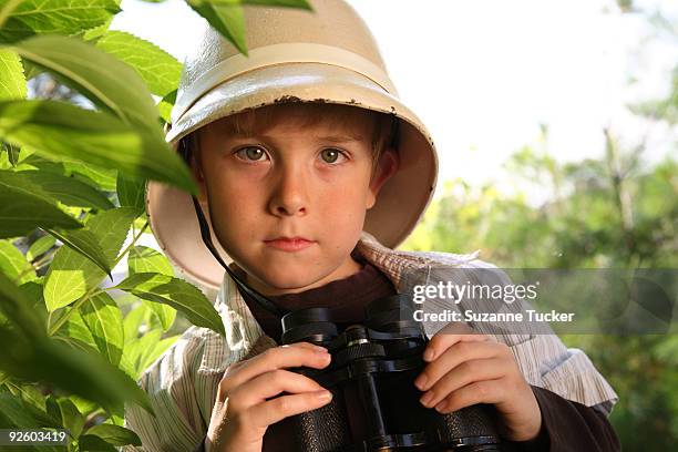 boy wearing a pith helmet holding binoculars - pith stockfoto's en -beelden