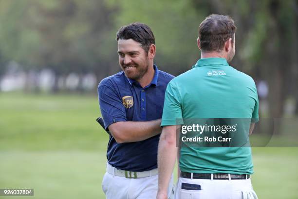 Louis Oosthuizen of South Africa shakes hands with Branden Grace of South Africa after making a par on the 18th hole during the first round of World...