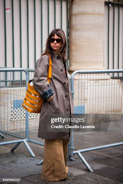 Natasha Goldenberg, wearing a brown trench and yellow stripped bag, is seen in the streets of Paris before the Ann Demeulemeester show during Paris...