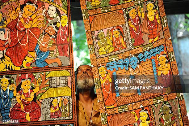 Indian traditional artist Khandu Chitrakar from West Bengal state hangs up Patta Chitra Katha paintings during a workshop at the National Institute...