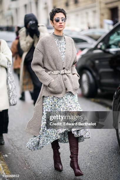 Yasmin Sewell wears a gray wool jacket, a flower print dress, leather boots, sunglasses , during Paris Fashion Week Womenswear Fall/Winter 2018/2019,...