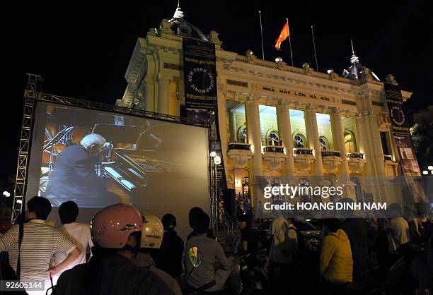 People watch piannist Emanuel Ax of the New York Philharmonic playing Beethoven's piano concerto No. 4 live broadcast on a large screen placed...