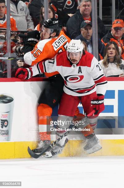 Jori Lehtera of the Philadelphia Flyers is checked into the boards by Justin Faulk of the Carolina Hurricanes on March 1, 2018 at the Wells Fargo...