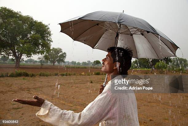 young indian farmer sheltering from monsoon rain  - monzón fotografías e imágenes de stock