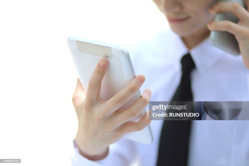 Businessman talking on smartphone with digital tablet outdoors