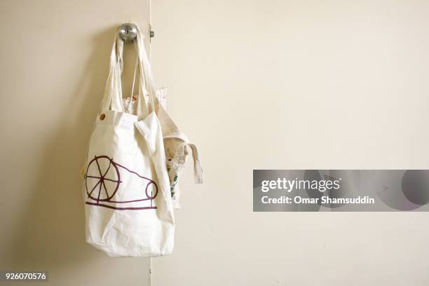 tote bag hanging on the door knob - bolsa de cor creme fotografías e imágenes de stock