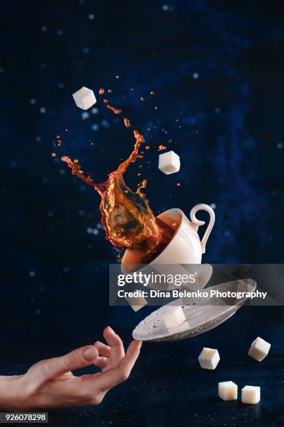 coffee cup with a dynamic splash balancing on a tip of a finger. balancing dishware with high-speed liquid motion. stage magician concept. - coffee drink splash stock pictures, royalty-free photos & images