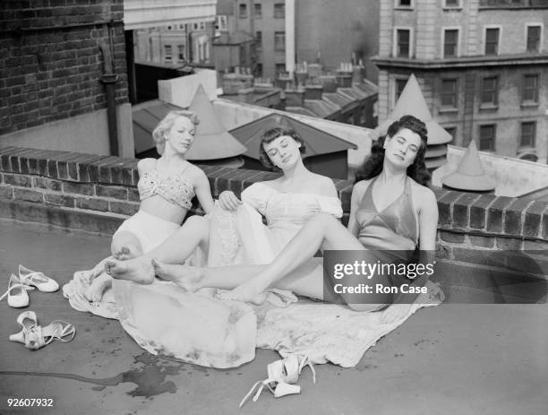 Chorus girls from the show 'Sauce Tartare' at the Cambridge Theatre in London, relax on the roof of the theatre, 28th June 1949. From left to right,...