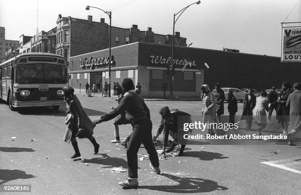 Following looting in the area, pedestrians drag debris from the street in front of a city bus at the intersection of West Madison Avenue and Oakley...