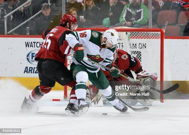 Jason Zucker of the Minnesota Wild and Jason Demers of the Arizona Coyotes battle for the puck in front of goalie Antti Raanta of the Coyotes during...