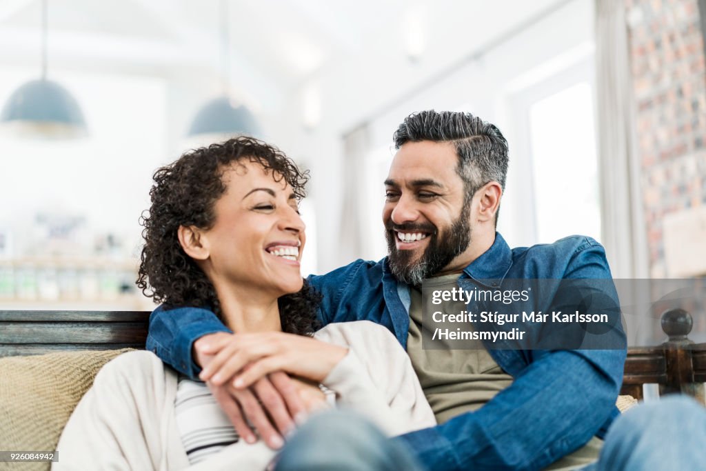 Smiling couple sitting on sofa at home