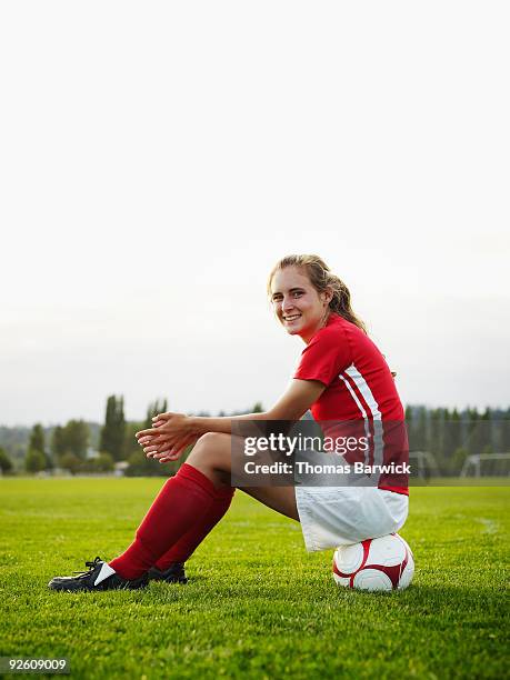 female soccer player sitting on soccer ball - girls in socks stockfoto's en -beelden