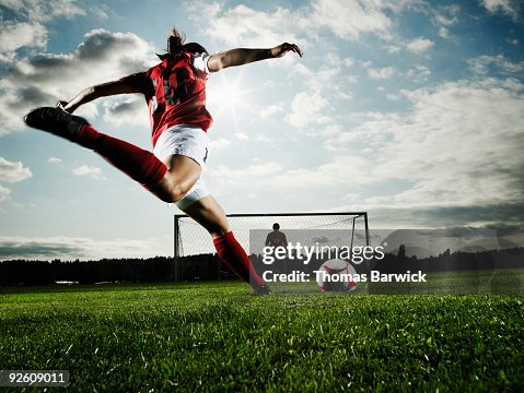 Female soccer player kicking ball toward goal Female soccer player kicking ball toward goal