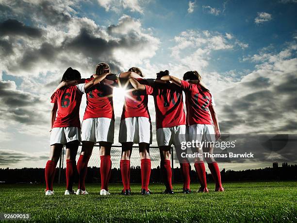 group of female soccer players embracing - american football field photos et images de collection