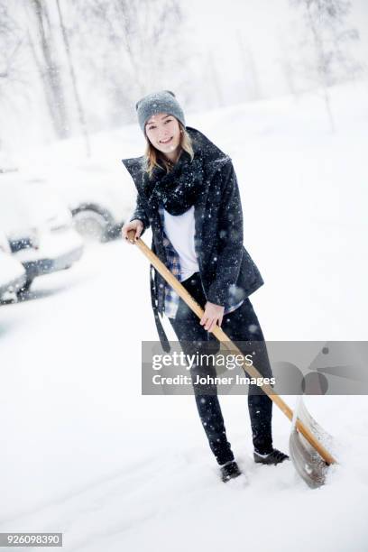 young woman shoveling snow - snow shovel stock-fotos und bilder