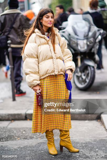 Guest wears a puffer coat, a checked pattern skirt, yellow boots , during Paris Fashion Week Womenswear Fall/Winter 2018/2019, on March 1, 2018 in...