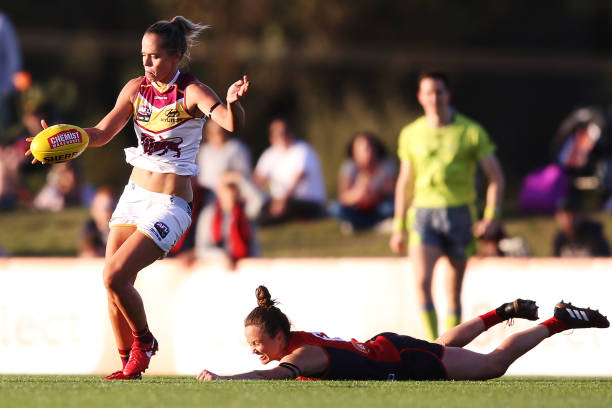 Emily Bates of the Lions kicks the ball from Daisy Pearce of the Demons during the round five AFLW match between the Melbourne Demons and the...