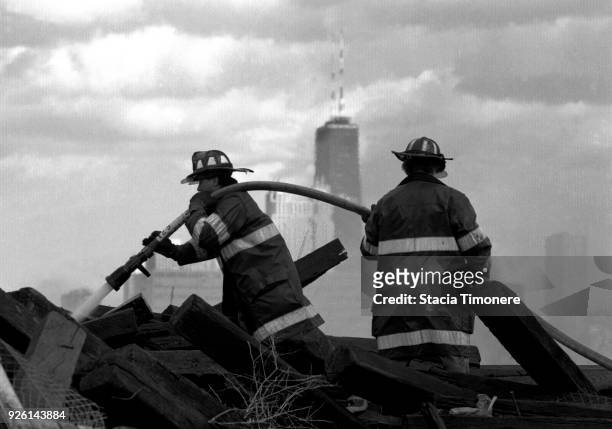 Chicago firefighters extinguish a rubbish fire on Goose Island with the Hancock Building in the background in Chicago, Illinois USA in 1993.
