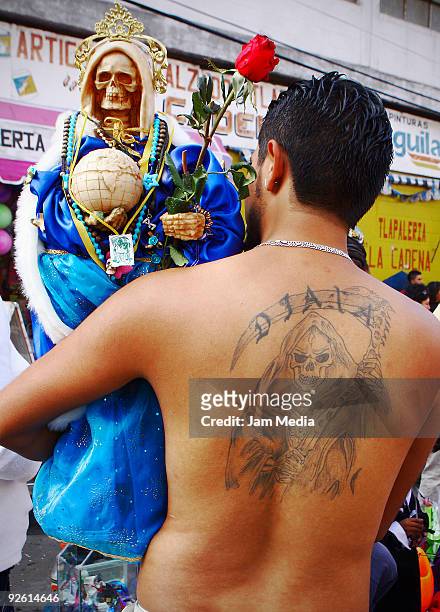 Devotee holds a figurine of Santa Muerte as part of the Dia de los Muertos celebrations at the Tepito district on November 1, 2009 in Mexico City,...