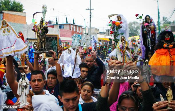 Devotees hold figurines of Santa Muerte as they parade in the deity's anniversary, part of the Dia de los Muertos celebrations at the Tepito district...