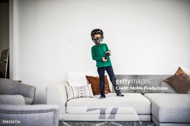 boy playing video games and wearing motorcycle helmet - funny hobbies stock pictures, royalty-free photos & images