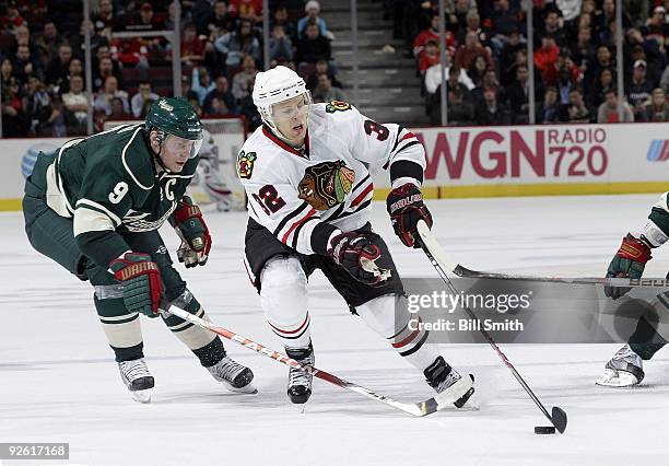 Kris Versteeg of the Chicago Blackhawks takes control of the puck as Mikko Koivu of the Minnesota Wild reaches from behind on October 26, 2009 at the...