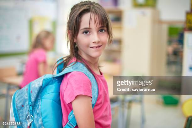 porträt von schulmädchen mit rucksack im klassenzimmer - pink shirt stock-fotos und bilder